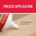 Close-up of adhesive tube applying precise bead on wooden surface with red label and white nozzle.