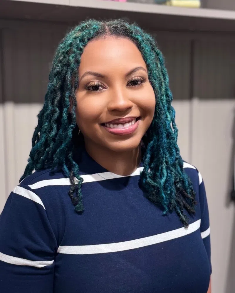 Smiling woman wearing a navy blue and white striped shirt standing indoors.