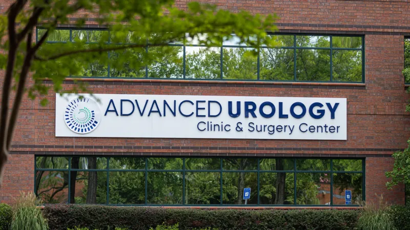 Exterior view of Advanced Urology Clinic & Surgery Center on a brick building with greenery and windows.