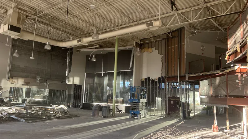 Interior of a large building under renovation with exposed ceilings, construction debris, and equipment.