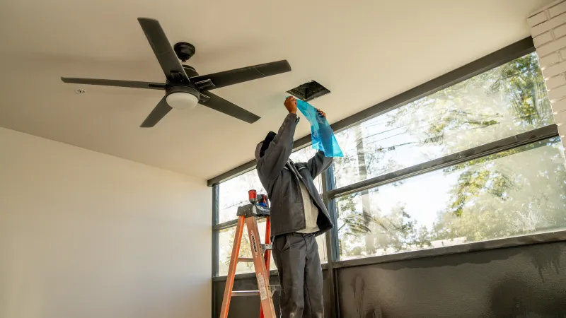 a person on a ladder painting a ceiling