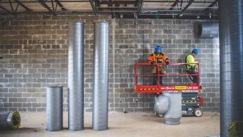 men in hardhats on a machine in a warehouse