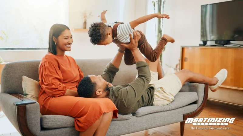 Happy family playing together on sofa in bright living room with natural light and modern decor