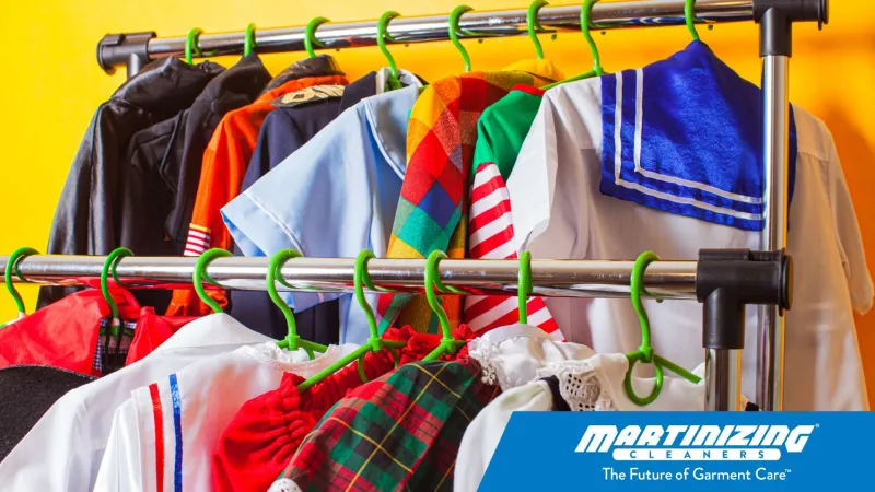 Colorful costumes and garments hanging on a rack with bright yellow background and Martinizing Cleaners logo