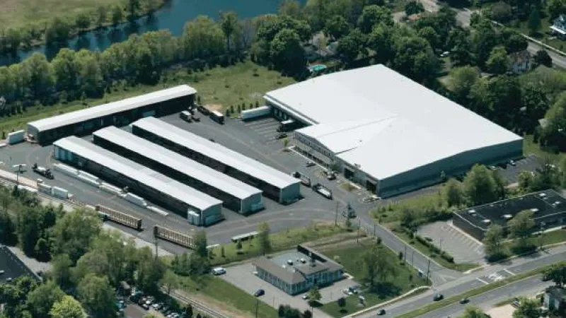Aerial view of a lumber yard with outdoor storage racks, stacks of wood, and a flatbed truck parked nearby.