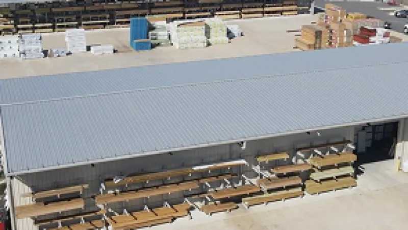 Aerial view of a lumber yard with outdoor storage racks, stacks of wood, and a flatbed truck parked nearby.