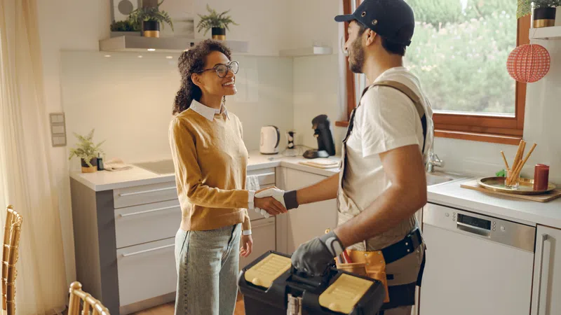 A handyman greeting a satisfied customer in a modern kitchen, showcasing service and professionalism.