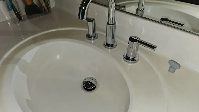 Modern white bathroom sink with sleek chrome faucet and soap dispenser reflected in the mirror above.