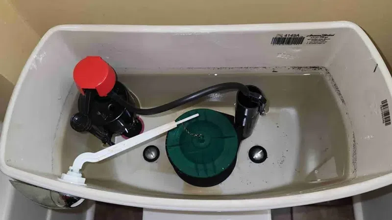 Open toilet tank showing internal components including fill valve, flush valve, and float mechanism.