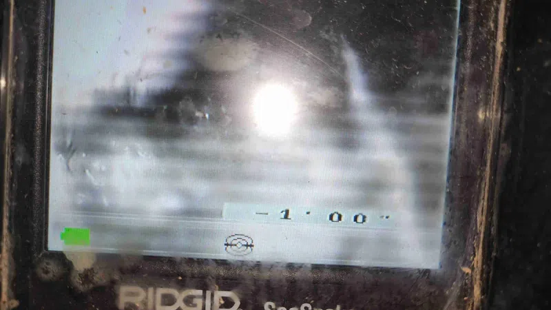 Close-up of a dirty RIDGID SeeSnake inspection camera screen displaying a submerged pipe interior.
