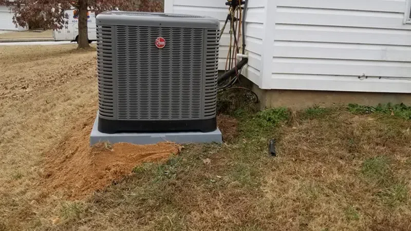 Rheem air conditioning unit installed outside a white house on a patch of dry grass.