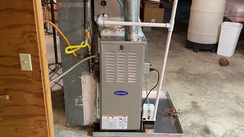 Carrier furnace unit installed in basement with ductwork and PVC piping on concrete floor.