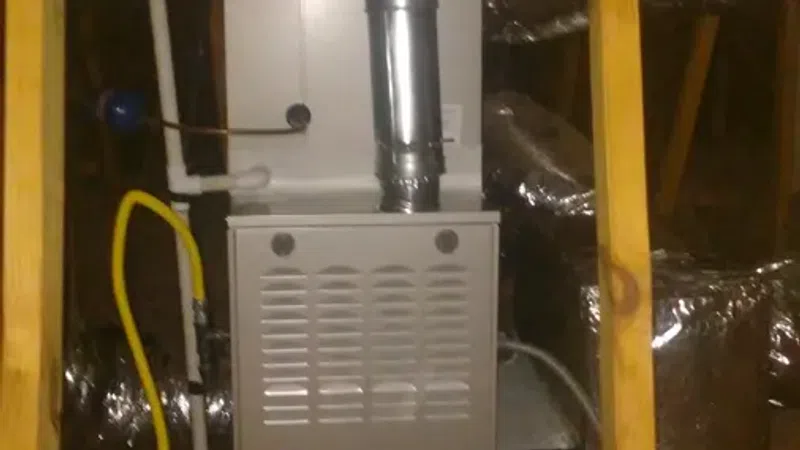 Carrier gas furnace installed in attic with surrounding ductwork and wooden framing