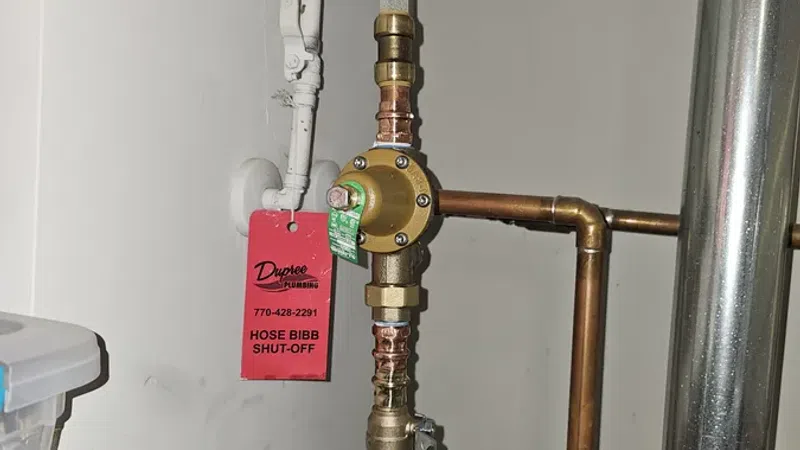 Indoor plumbing setup with copper pipes, a shut-off valve tagged 'Hose Bibb Shut-Off', and insulated pipe sections.