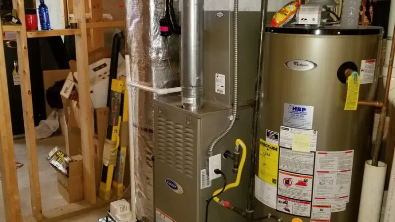 New furnace and water heater installed in an unfinished basement with insulation and exposed framing.