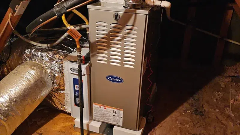 Carrier furnace and ductwork installed in an attic with exposed wooden beams and insulation.