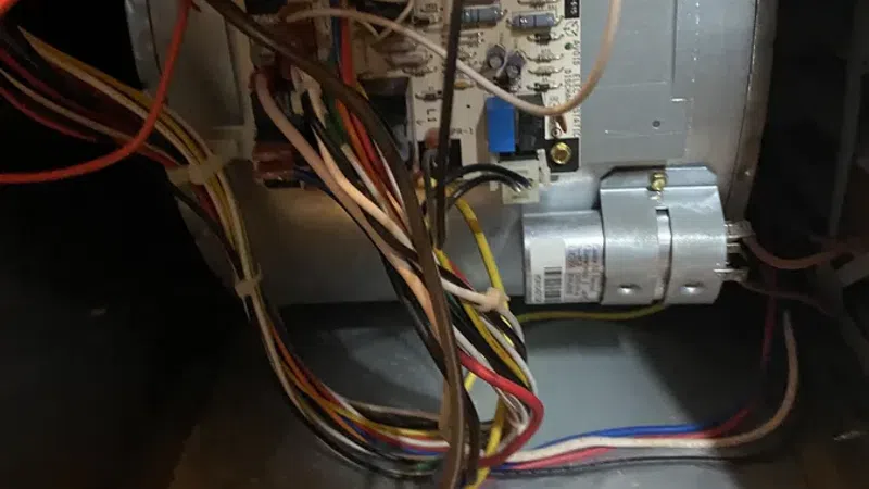 Close-up of an electrical control board with multicolored wiring inside mechanical equipment housing.
