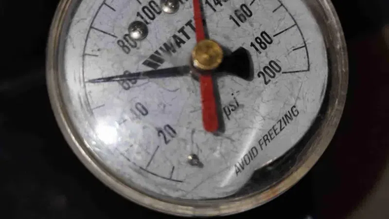 Close-up of a pressure gauge showing 120 psi with a brass fitting and warning to avoid freezing.