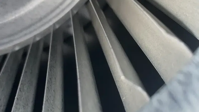 Close-up view of gray metal turbine blades inside an industrial fan or jet engine component.