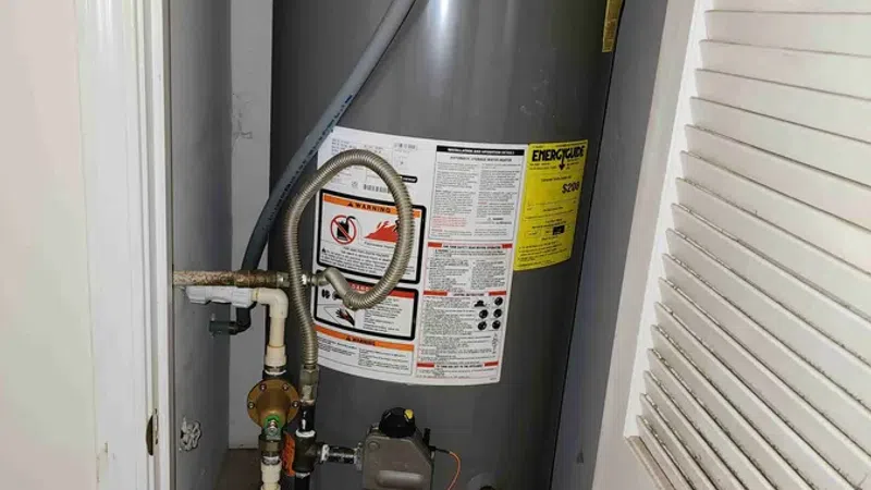 Rheem Classic Series Professional water heater installed in a small closet space with connected pipes and valves.