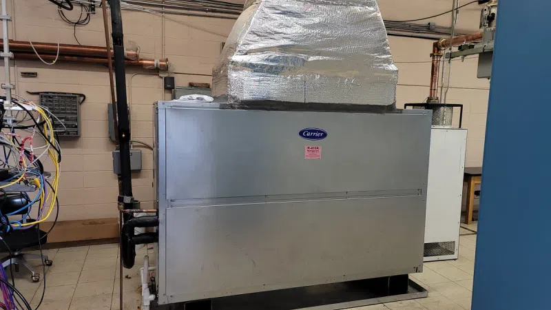 Large industrial Carrier HVAC unit with ductwork and wiring installed in a commercial building room