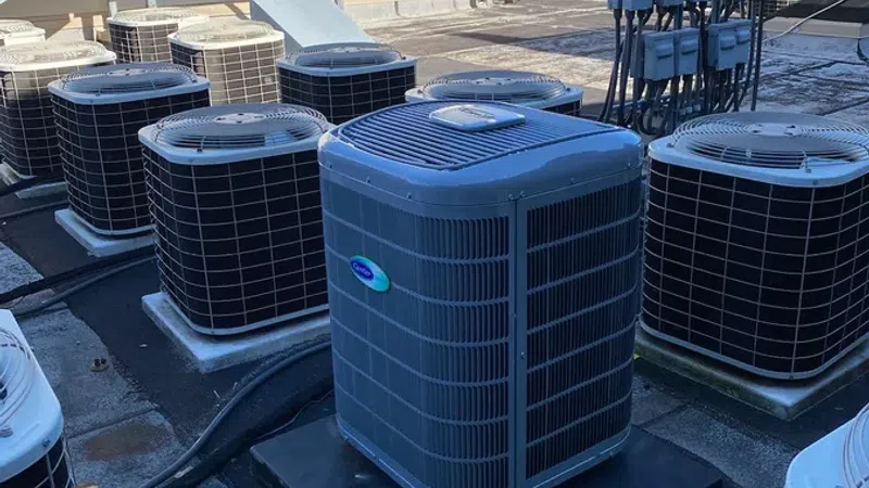 Multiple rooftop air conditioning units installed on a commercial building under clear blue sky.