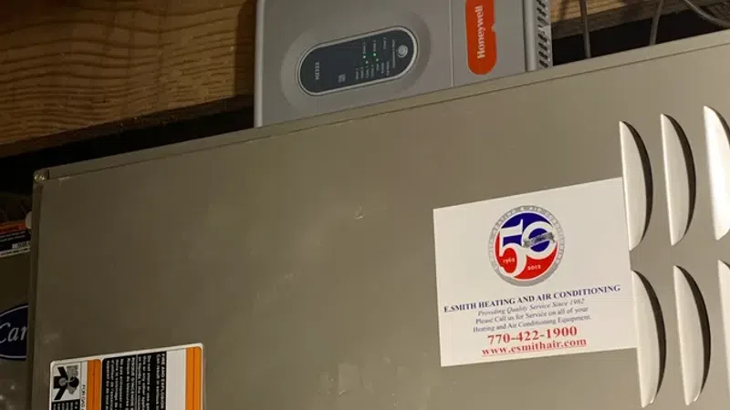 Heating and air conditioning system installed in a wooden attic space, featuring Honeywell device and warning labels.