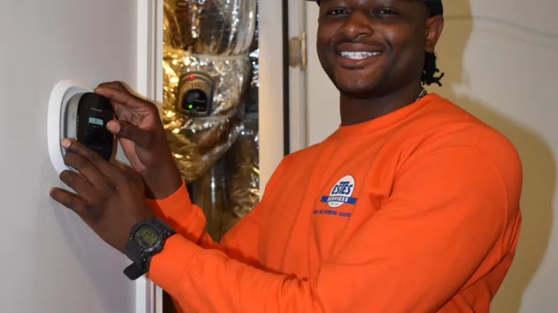 Estes Services Maintenance Tech working on a Eco bee thermostat