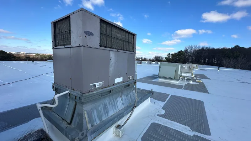 Rooftop HVAC units installed on a flat commercial building under a blue sky with scattered clouds.
