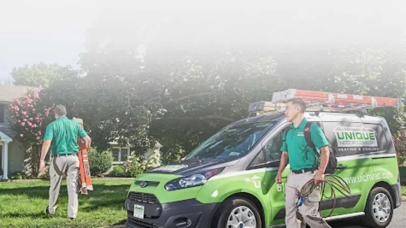 a couple of men standing next to a green car with a firetruck in the background