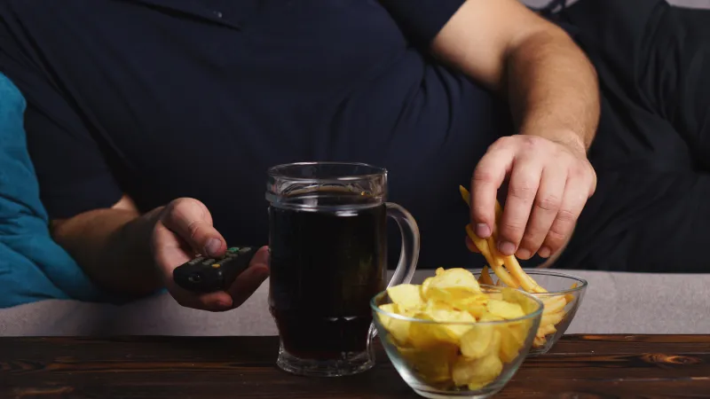 a man holding a phone and a bowl of fruit next to a glass of beer