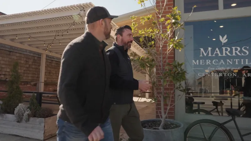 Two men walking and talking outside Marrs Mercantile storefront in Centerton, Arkansas on a sunny day