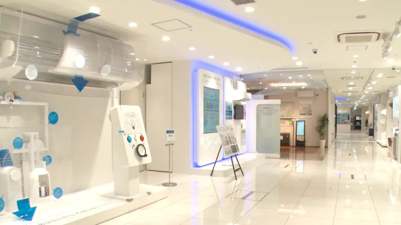 Modern showroom displaying various air conditioning systems and technology with bright white interior and blue accents.