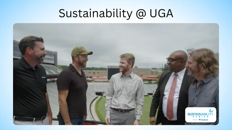 Five men stand and smile in a stadium setting under Sustainability @ UGA banner, discussing sustainability initiatives.