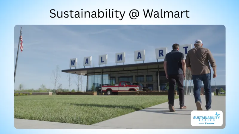 Two men walk towards a Walmart building with a vintage red and white truck displayed outside under a clear blue sky.