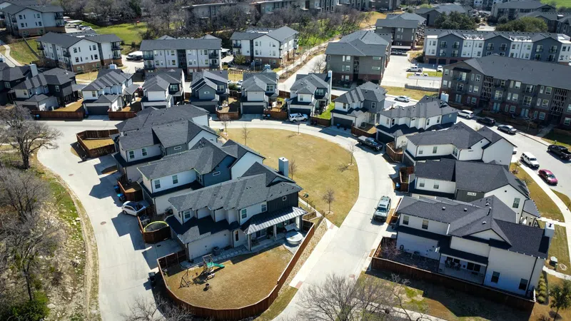 Aerial view of a modern suburban neighborhood with single-family homes and curved streets under daylight.
