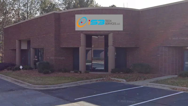Exterior view of a brick office building with IS3 Tech Services sign above the entrance and empty parking spaces.