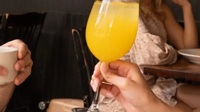 Group enjoying breakfast with coffee, brunch dishes, and orange drinks in a cozy restaurant setting.