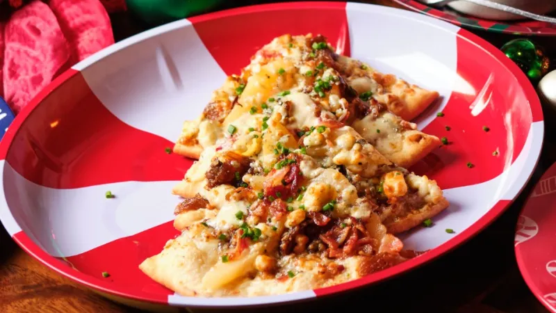 Holiday meal with festive plates of food surrounded by Christmas ornaments and a lit red candle.