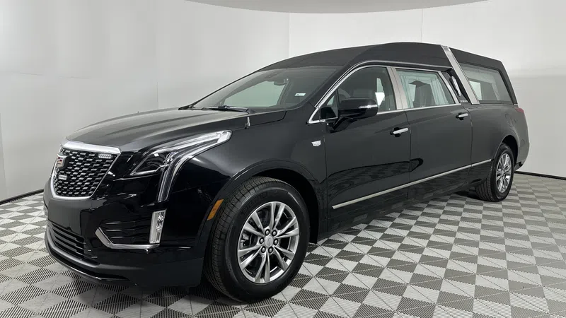 Black luxury Cadillac hearse parked on checkered floor with sleek design and chrome accents.