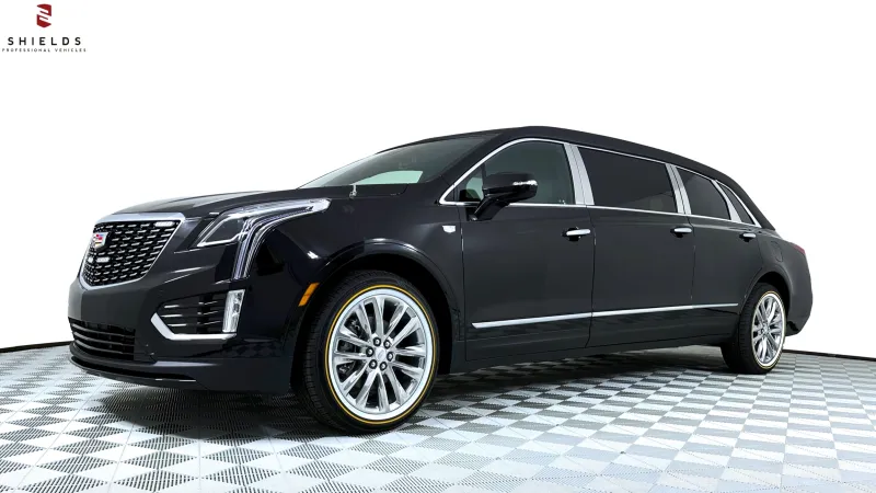 Luxury black Cadillac limousine with stylish wheels parked in a bright studio setting.