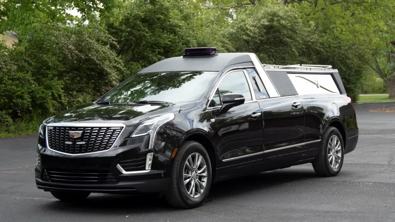 Custom black Cadillac hearse parked in a scenic outdoor setting.