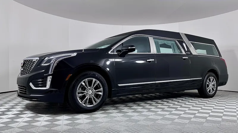 A sleek black Cadillac hearse parked in a modern showroom setting.