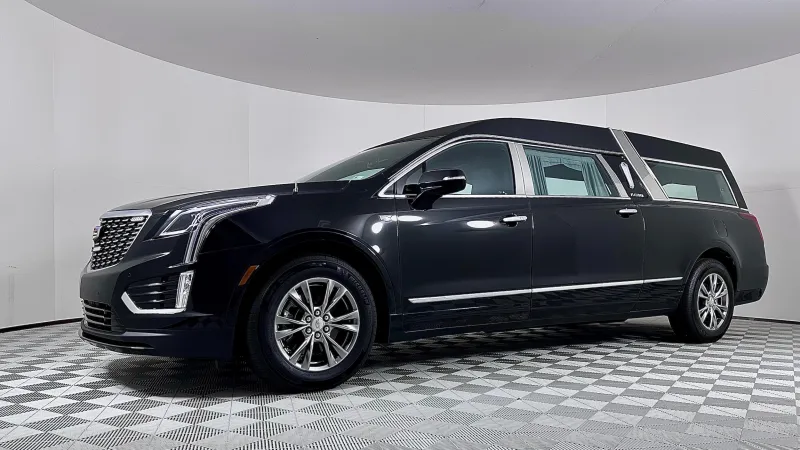 A sleek black Cadillac hearse parked in a modern showroom setting.