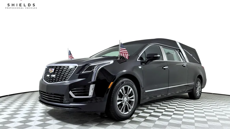 A sleek black Cadillac hearse adorned with American flags, showcasing luxury and sophistication.