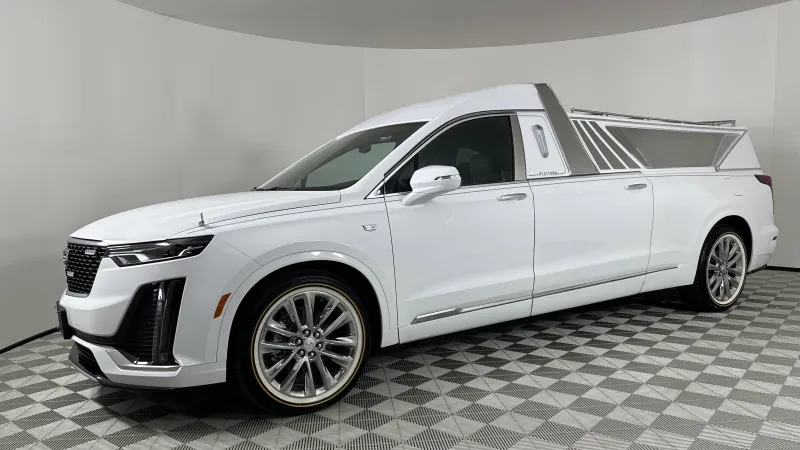 White stretched Cadillac Escalade pickup with custom rear design in a showroom with checkered floor.