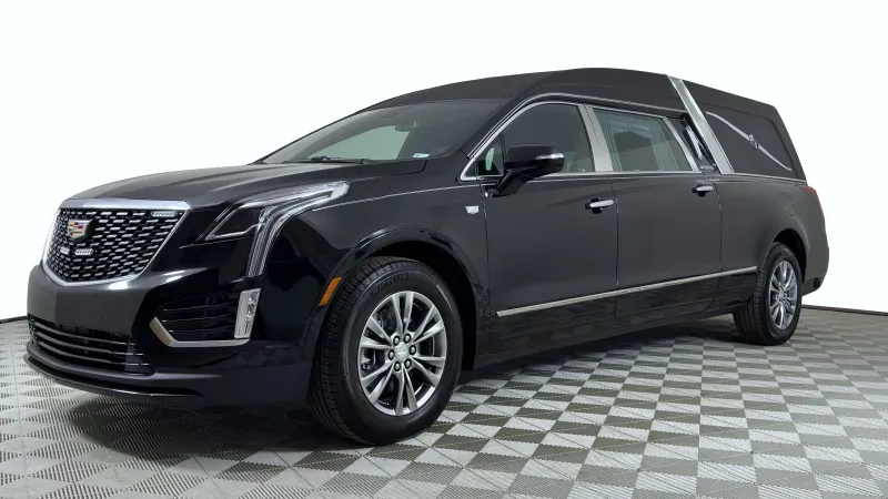 Black Cadillac hearse with chrome accents on checkered floor under bright lighting