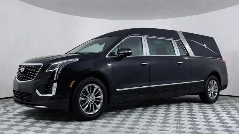 Black Cadillac luxury hearse with extended body and sleek chrome accents in a white showroom.