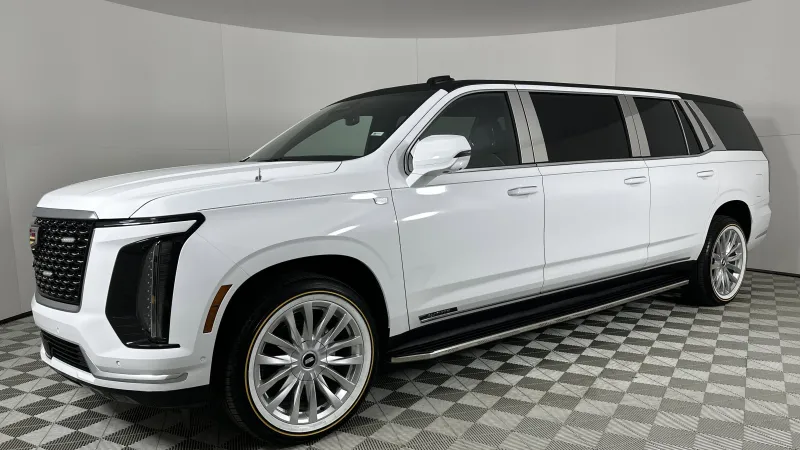 White luxury stretched SUV limousine with tinted windows and large alloy wheels in a showroom.