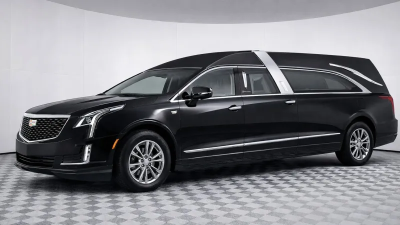 Black Cadillac hearse with sleek design parked on a checkered floor in a white studio environment